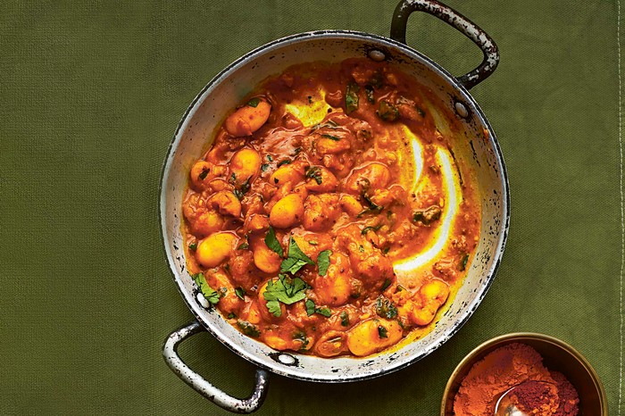 A metal pan filled with a bean curry with green herbs on top