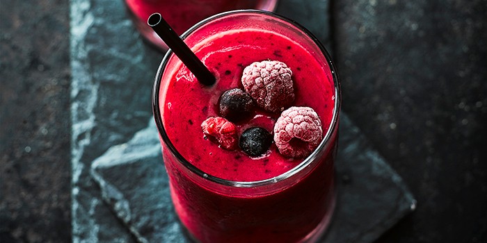 Frozen berry smoothie in a glass with a straw