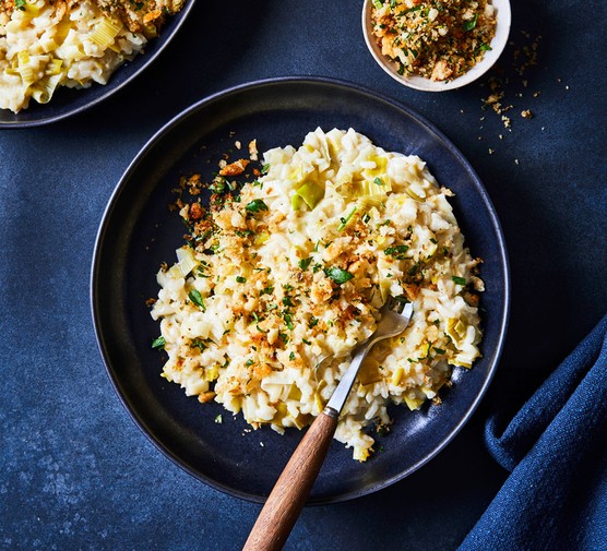 Leek risotto in a bowl topped with fried anchovy and breadcrumbs