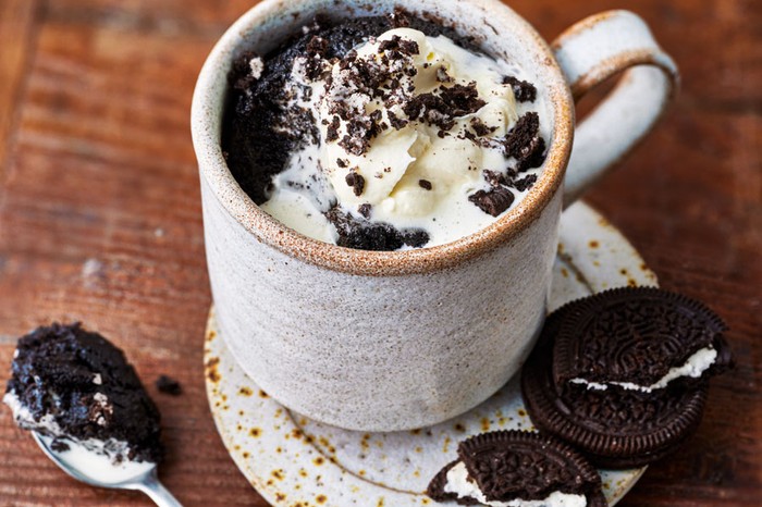 Mug of oreo cake next to some Oreos